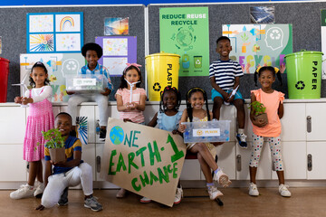 Portrait of happy diverse children with ecology items and plants in class at elementary school - Powered by Adobe