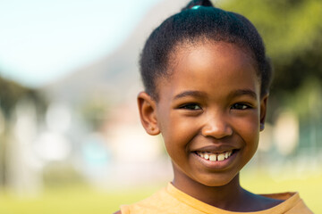 Portrait of african american schoolgirl smiling in sports field at elementary school