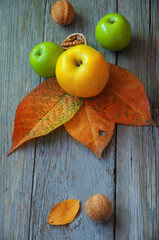 Autumn leaves, apples and walnuts. Rustic food. Homeliness. Autumn background with leaves, fruits and an old wooden table.