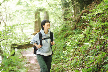 新緑の山道を歩いている若い日本人女性 - obrazy, fototapety, plakaty