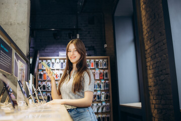Portrait of happy young woman buying a new smartphone in store. Shopping a new digital device.