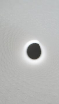 Vertical video. An abstraction, the camera inside a white tunnel with rapidly moving beams of light, a hyperloop concept.
