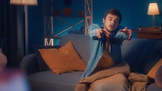 Male sleepwalker sits on a sofa in the living room close up. Somnambulism.