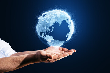 Close up of man hands holding glowing globe hologram on blurry blue background. Digital earth and metaverse concept.