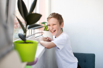 A cute boy looks out the window of a white balcony and laughs.