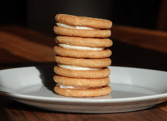 A closeup of a stack of cream sandwich biscuits on a white plate. 