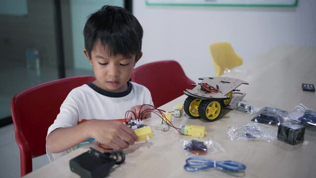 Kindergarten asian student learn in coding robot car and electronic board cable in STEM Arduino, Computer code in robotics for kids.