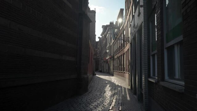 Sunlight glimmers in shadow alley way of Oudekerkplein Amsterdam Red Light District De Wallen