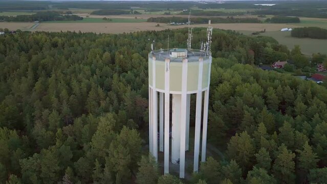 Water tower in countryside village in Sweden. Drone spiral zoom-in orbit shot.