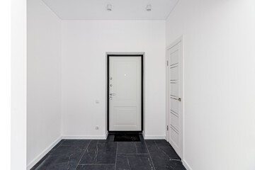 Empty renovated room in light colors with a black door. The front door to the house