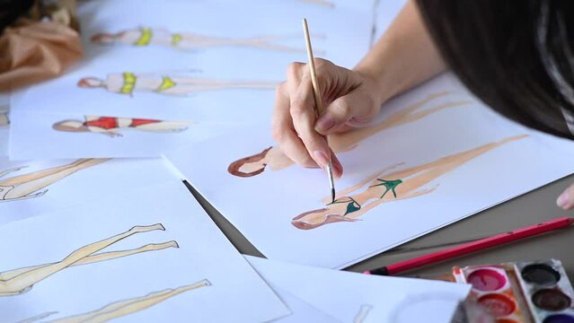 Faceless woman draws sketches of swimwear. Close-up of fashion designer's hands.