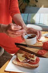 a woman in a bright orange dress preparing bruschetta for breakfast on the balcony of an apartment in a cozy interior, top view, close up