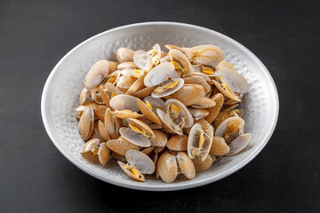 tasty fresh steamed baby clam in metal plate on dark tone texture background, simply seafood recipe menu