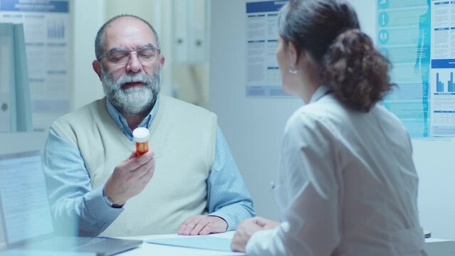 Female doctor giving pills to senior male patient and telling his medication dose during appointment in clinic