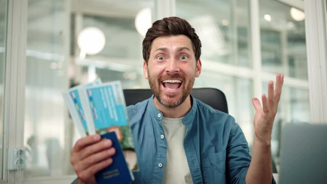 Happy excited office worker holds a passport with vacation tickets, looks into the camera, and enthusiastically shouts wow, last day of work in the office before going on vacation with their family.