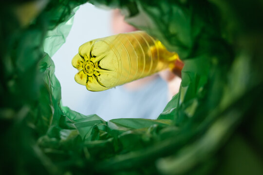 Low angle view unrecognizable man sorting yellow plastic bottles products recycling bin POV. Waste segregation, waste sorting, waste recycle. Conscious consumption of plastic.