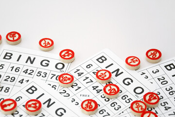 Many wooden chips with numbers and cards for a board game of bingo or lotto on a light background.