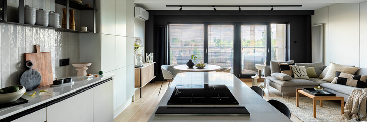 Modern composition of kitchen space with design kitchen island, black hookers, grey table, flowers,...