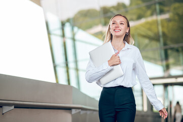 Business woman in pants and white blouse walking iand looking confident