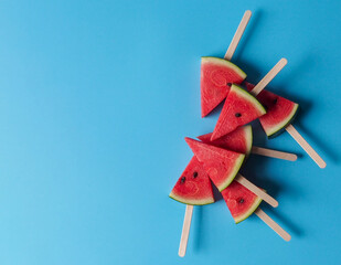 Slice watermelon popsicle sticks top view on blue color background with copy space for summer fruit concept.