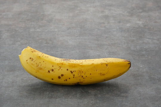 The bananas is medium ripe with brown spots all over the yellow skin. Close up and copy space.
