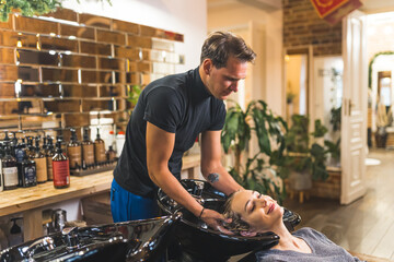 Hairdresser shampooing his client hair at a sink in a barber shop before haircut. High quality photo