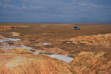 Landscape of multi-colored clay dunes. Mars on earth. Blue car. 
