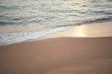 Fototapeta na wymiar Ocean wave on sandy beach in twilight time background with sunlight reflection on wet sand. 