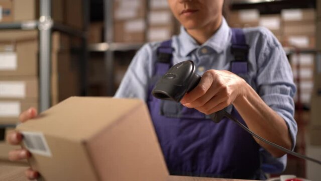 Female warehouse worker scanning barcode on delivery parcel. Woman scan barcode of cardboard packages before delivery at storage.