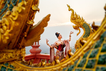 Wide shot of beautiful Asian woman with Thai traditional dress stand with Thai dance action in...