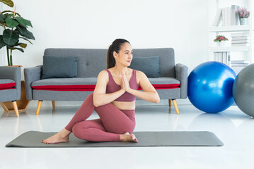 Asian young healthy woman in sportware practicing yoga at home, Sport girl meditating  in living room at home