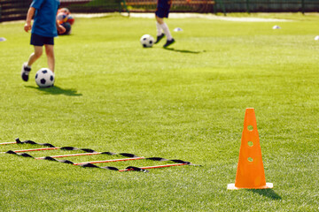 Obraz premium Football Training Field at School Pitch. Children Playing at Soccer Field. Training Ladder and Cone on Grass Turf. Soccer Education Unit During Summer Practice Camp