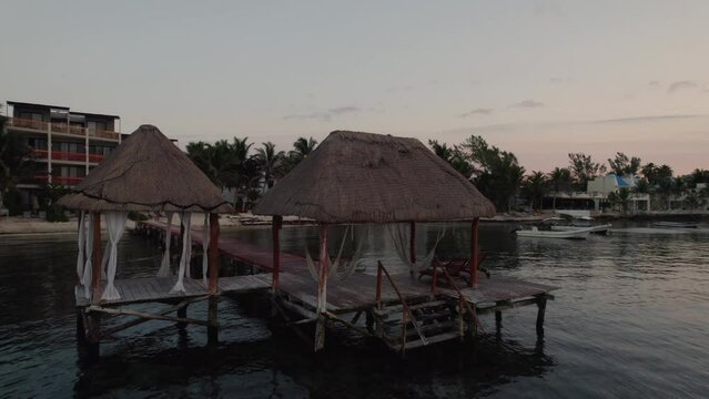 Aerial view rotating around wooden deck in front of the beach in Alea, Tulum during sunset.