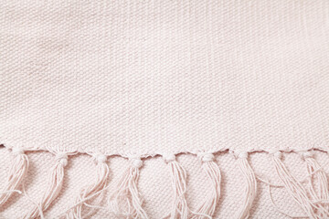 Textile product with long fringe lies on white fabric..