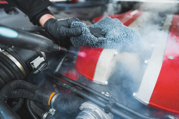 getting car engine cleaned with a cloth and hot steam, auto repair shop. High quality photo