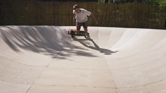 A cool guy rides in a skate park on a skate surf. A skilled young man is free to skateboard.