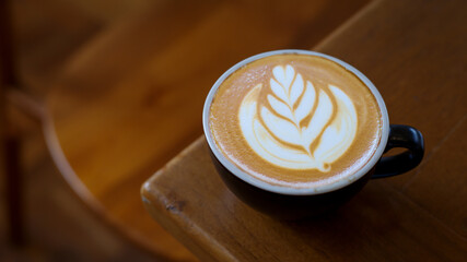 A cup of cappuccino coffee with soft foam on a wooden table. The coffee moment concept is everywhere.