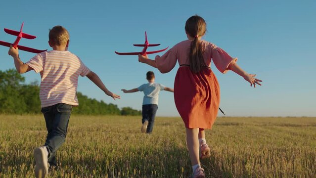 Kids fly, running. Children boy, girl play in park sky. Child plays with toy plane, dream is to fly to travel, kids play together. Creative imagination of children, active play in nature. Happy family