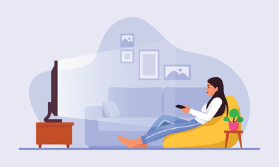 A cute girl is sitting in front of the TV with a remote control in her hands and watching something.