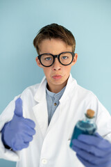 young mad scientist boy with white coat and blue gloves and blue liquid