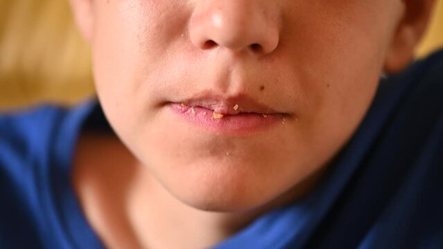 A close-up of a teenage boy chewing a bun