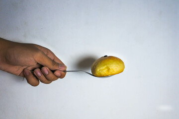 a hand holds a metal spoon filled with bread on a white background