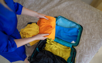 Woman is packing clothes into suitcase. Getting ready for the trip.