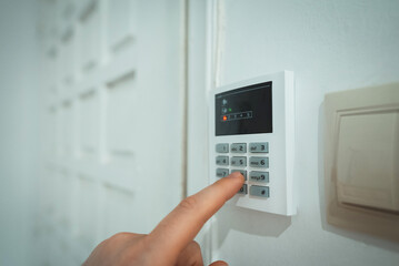 Man putting code in alarm system panel at home.