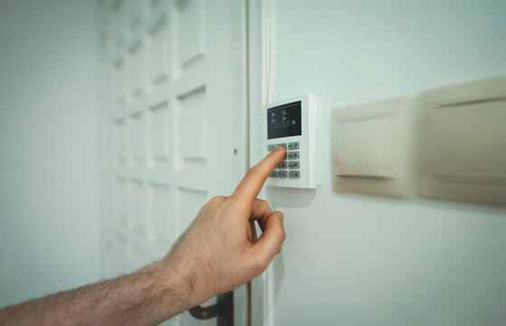 Man putting code in alarm system panel at home.