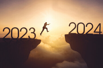 Businessman jumping gap on the cliff from number 2023 to number 2024