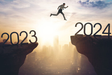 Caucasian businessman jumping gap on the cliff from number 2023 to number 2024