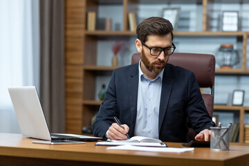 Obraz premium Serious thinking businessman behind paper work, senior experienced boss working concentratedly sitting inside office at table, financier investor signing contract.