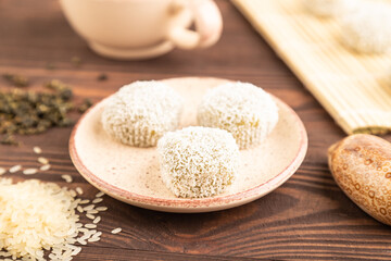 Japanese rice sweet buns mochi filled with pandan and coconut jam on brown wooden, side view, selective focus
