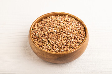 Naklejka premium Raw buckwheat on white wooden, side view